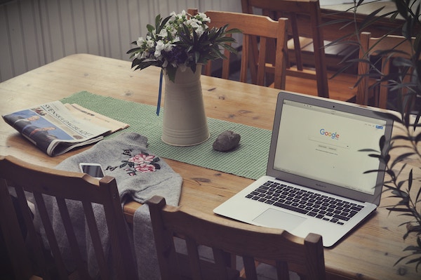 Laptop open to google on tabletop, flowers, notebook , lisa laporte using google analytics