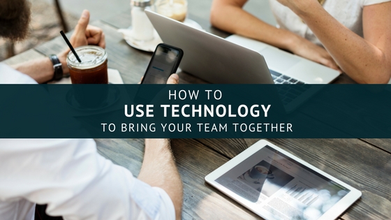 People sitting across from each other at a table, one on a laptop, the other using a phone, image used for Lisa Laporte blog on how to use technology to bring your team together